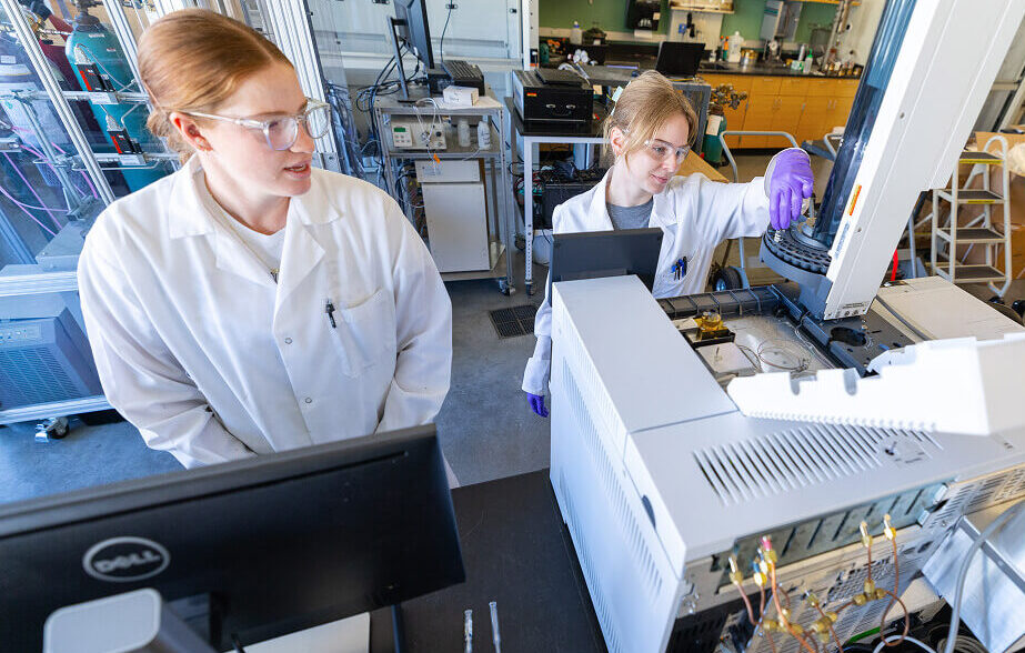 Two scientists in lab coats working with equipment in a bright, modern laboratory.